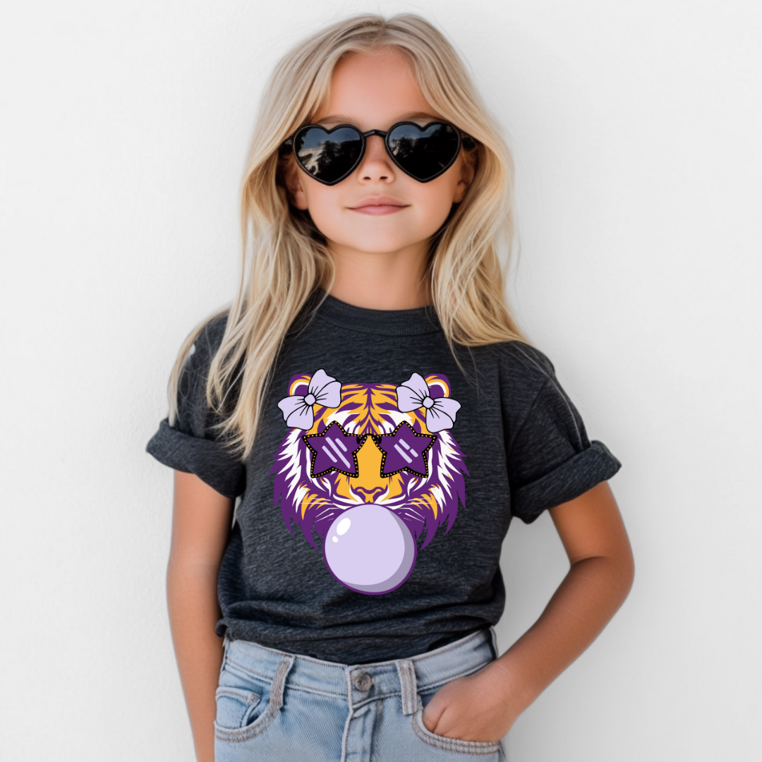 Child wearing a dark gray t-shirt with a purple tiger graphic, sunglasses, and light blue jeans on a white background.