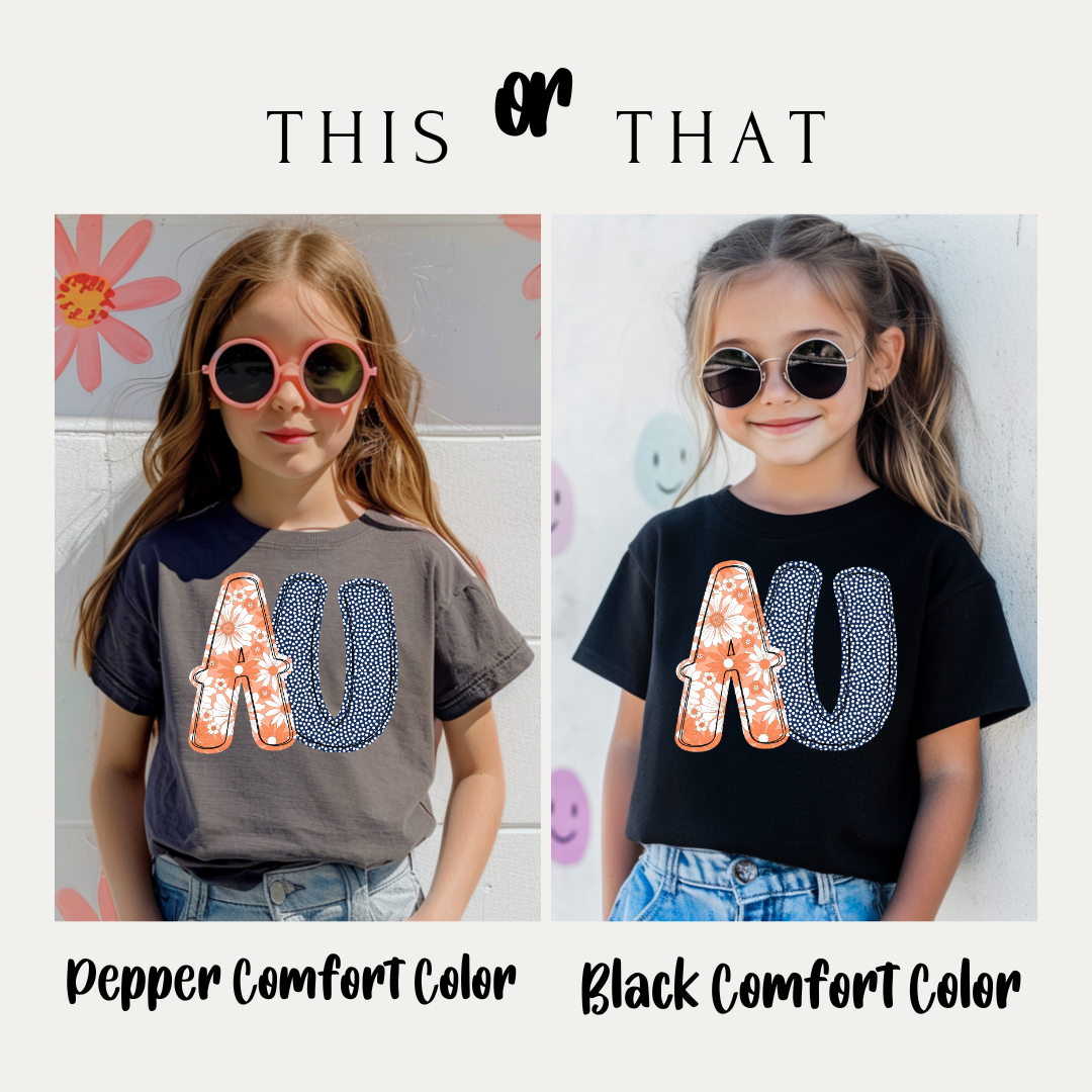 Two children wearing shirts with 'AU' design, one in pepper comfort color and one in black comfort color.