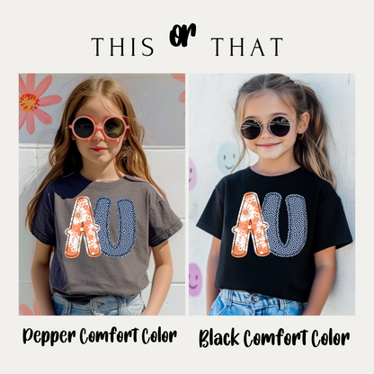 Two children wearing shirts with 'AU' design, one in pepper comfort color and one in black comfort color.