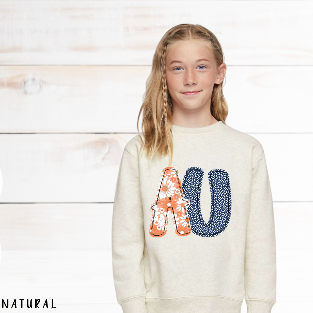 Young girl wearing a cream sweatshirt with colorful letters on a wooden background