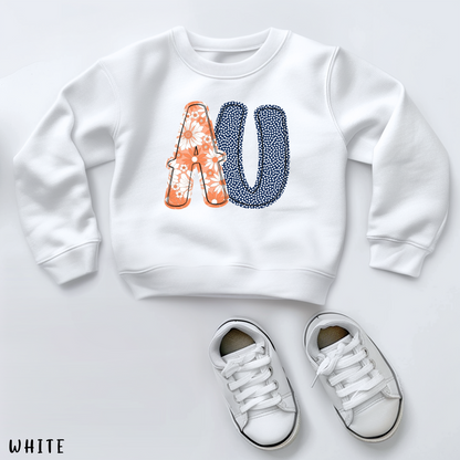White sweatshirt with colorful letters 'AU' and white sneakers on a light gray background