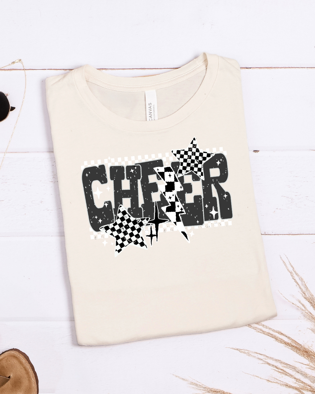 Beige t-shirt with 'CHEER' design on a white wooden background