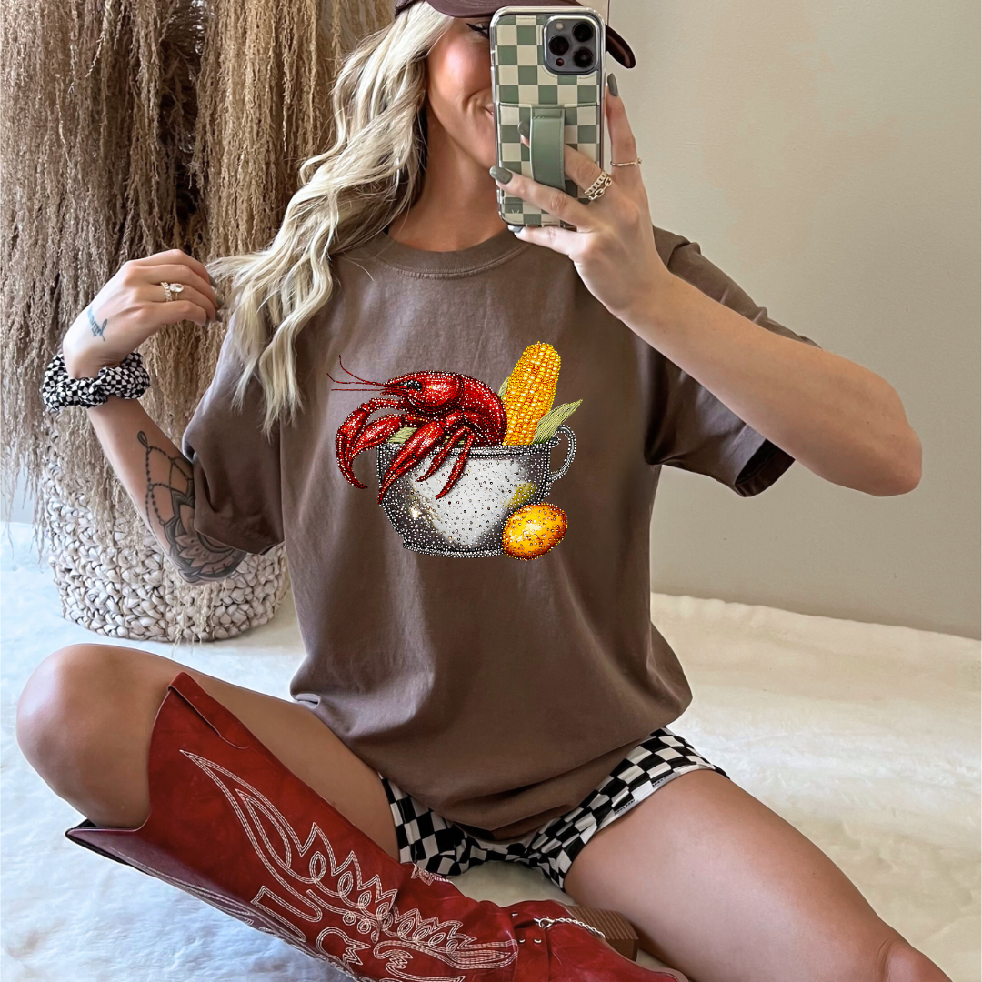 Person wearing a brown t-shirt with a crawfish graphic design