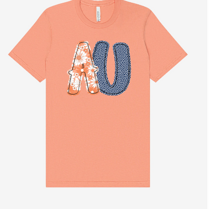 Peach-colored t-shirt with floral and polka dot letters 'AU' on a white background