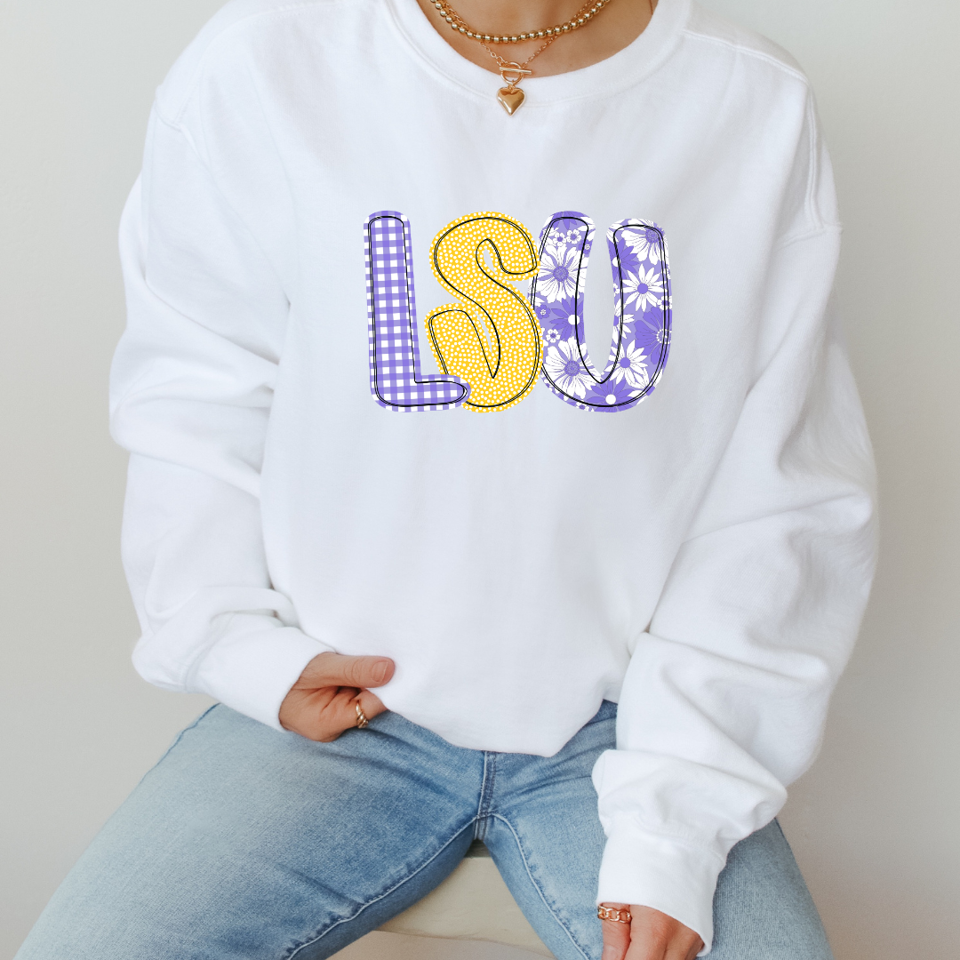 White sweatshirt with colorful 'LSU' letters worn by a person.