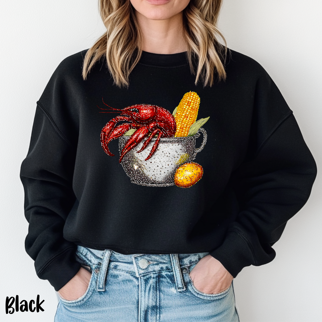 Black sweatshirt with crawfish and corn design worn by a person against a white background