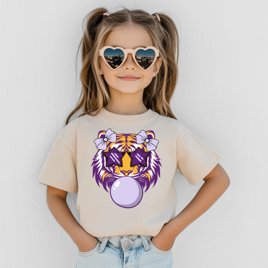Child wearing a t-shirt with a tiger design and heart-shaped sunglasses against a white background